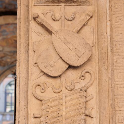 dettaglio bassorilievi arco portale con strumenti musicali